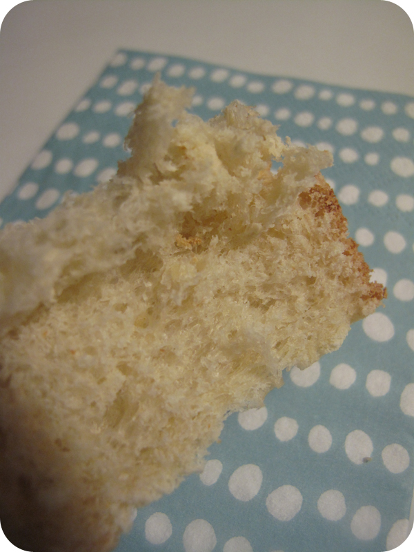 Torn piece of soft white bread with golden crust on a blue and white polka-dot napkin