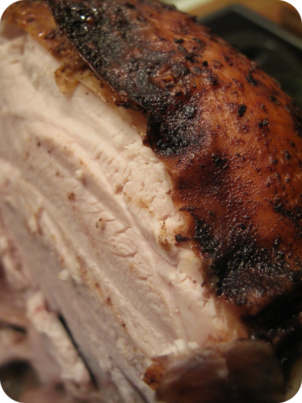 Close-up of sliced roasted meat with a dark charred crust and pale interior